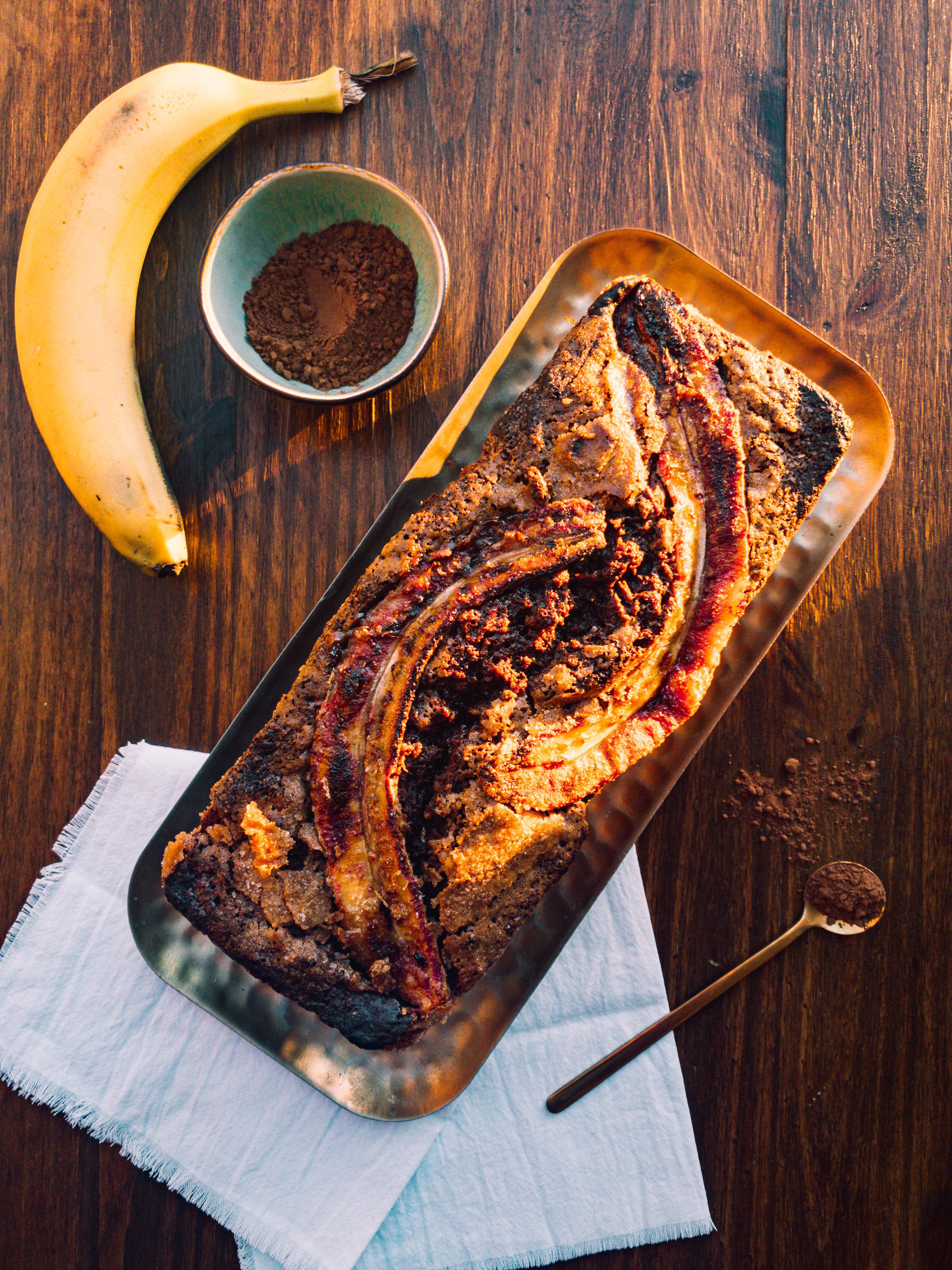 banana bread with banana, cinnamon, and nuts on top.